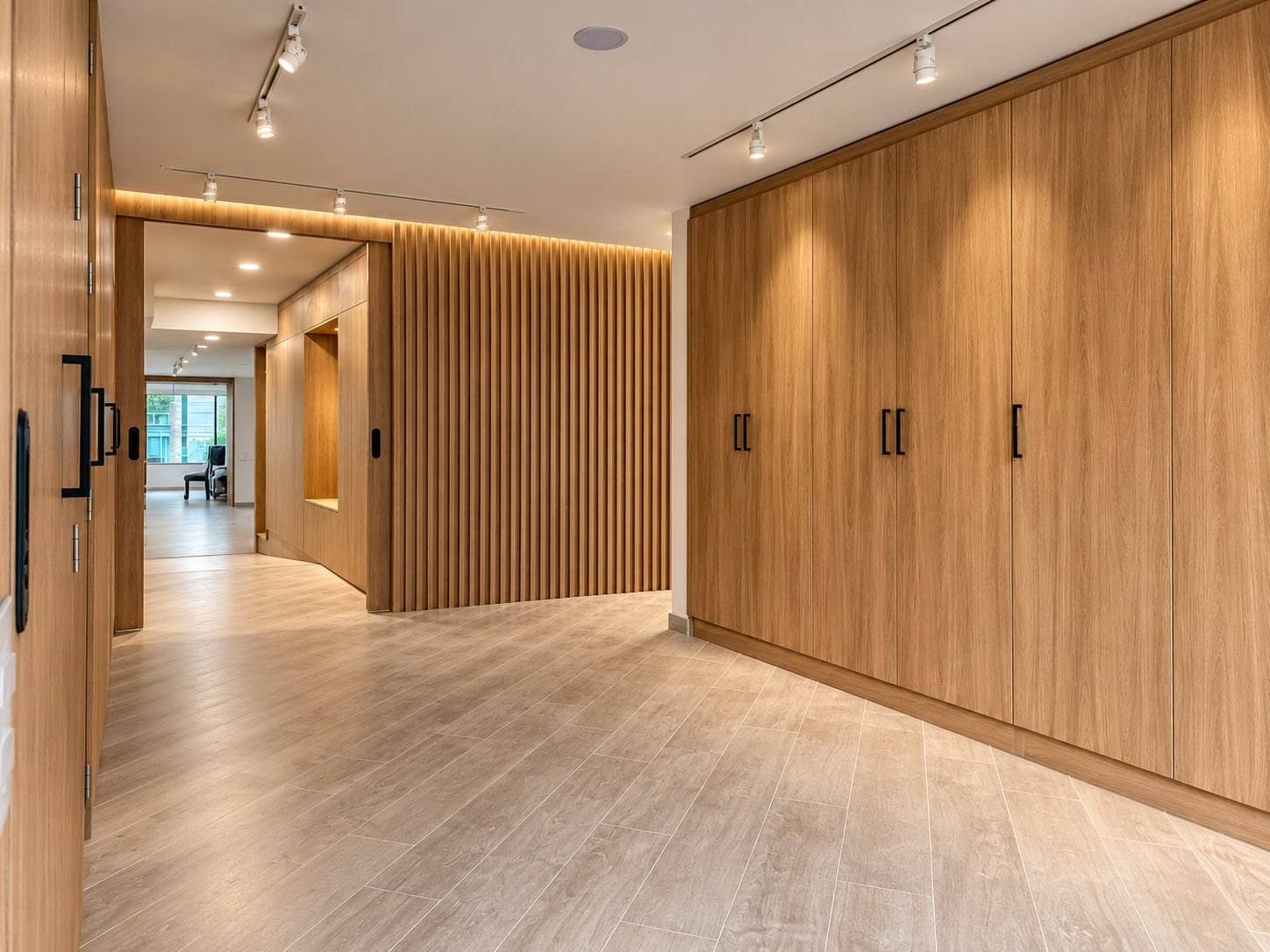 Pasillo con clósets de piso a techo en madera y muro de listones iluminado.