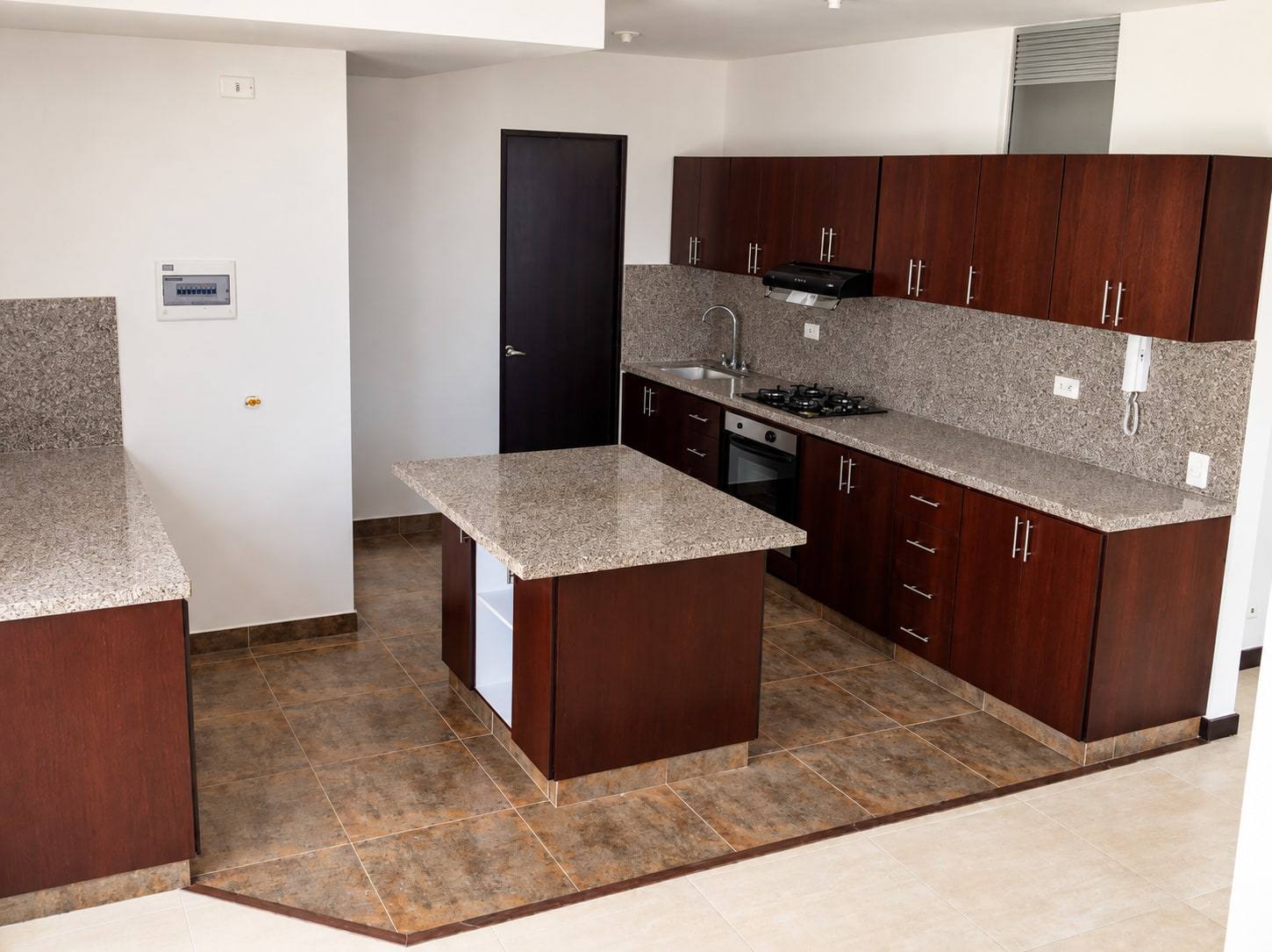 Cocina en madera oscura con isla y mesón de granito.
