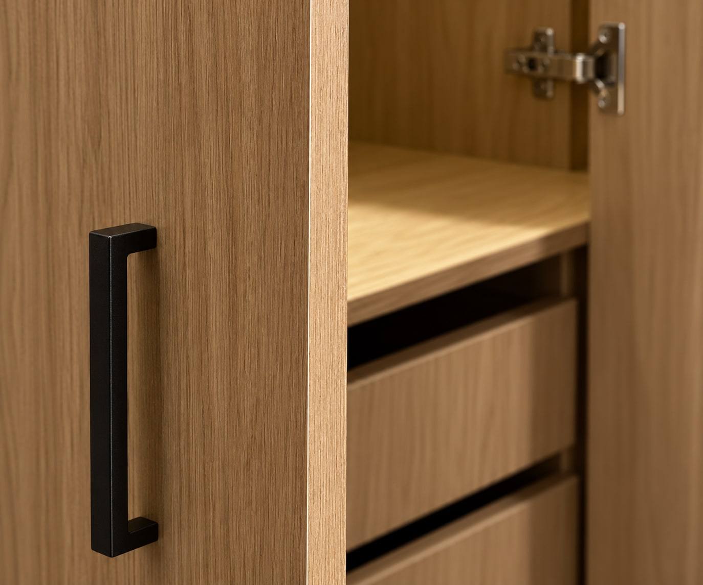 Puerta con manija negra y cajones interiores de un clóset en madera.