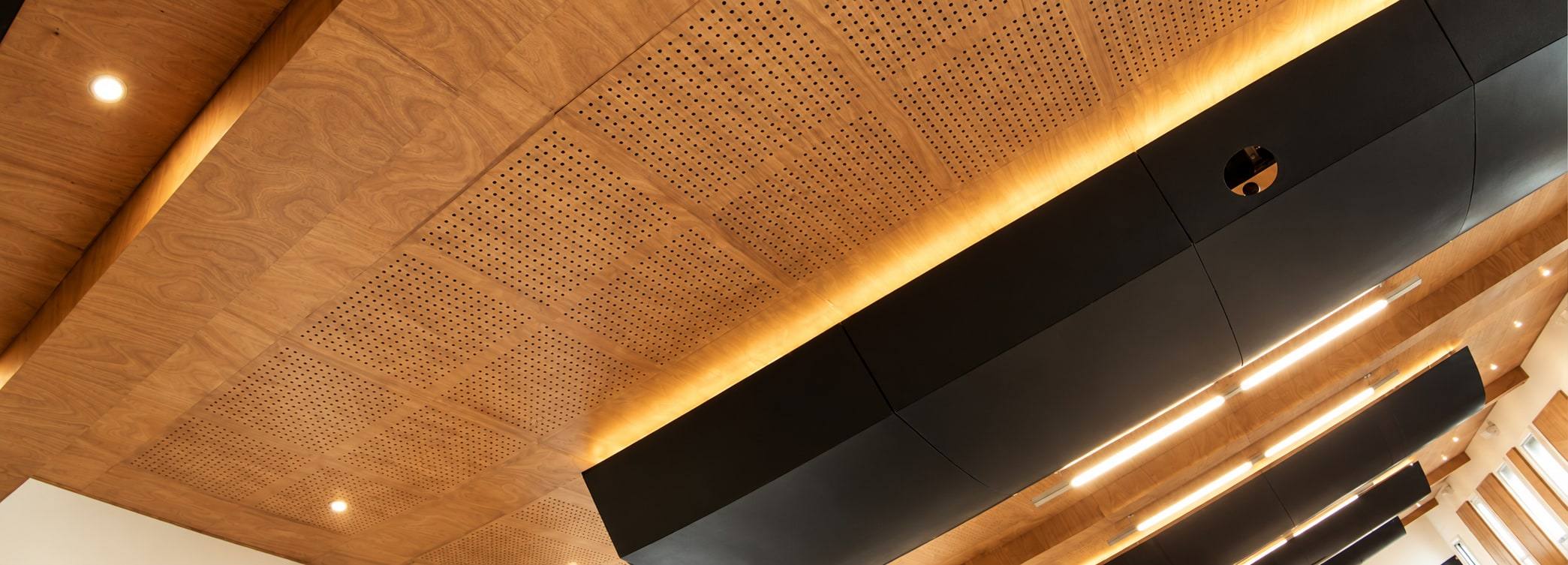 Techo acústico de madera perforada con luz indirecta.